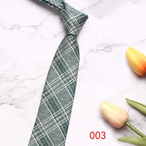 Detailed shot of green plaid necktie fabric texture and knot design on marble background.