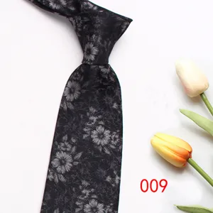 Close-up detail of a stylish black necktie featuring intricate grey floral patterns.