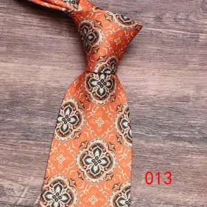 Orange paisley pattern tie detail shot, classic floral necktie accessory for men.