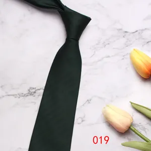 Detailed view of dark green herringbone silk tie, elegant business style with floral prop background.
