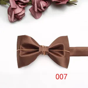 Dettaglio di papillon marrone in raso con catena dorata per eleganti abiti formali.