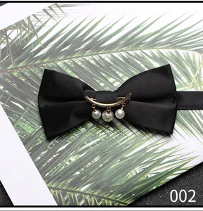 Vista ravvicinata di un elegante papillon nero in satin con metallo dorato e perle.