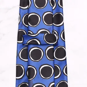 Blue silk necktie featuring a bold black and white circle pattern, detailed close-up shot.