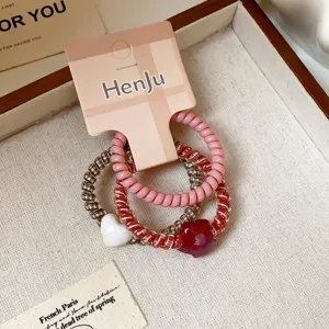 Close-up detail shot of cute heart pendant spiral hair ties set with branded packaging card.