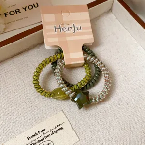 Close up of green spiral hair ties set with star pendant, chic and playful detail view.