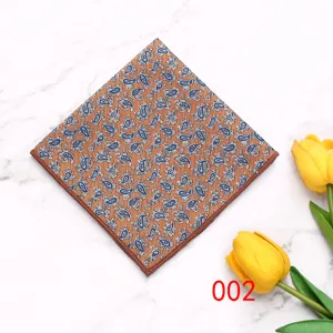 Detail shot of men brown pocket square with blue paisley pattern on marble background.
