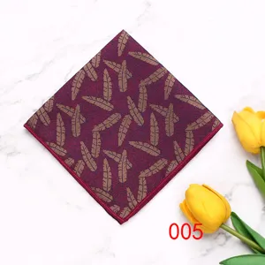 Detail shot of a men's polyester pocket square featuring a stylish gold feather pattern on a deep red fabric.