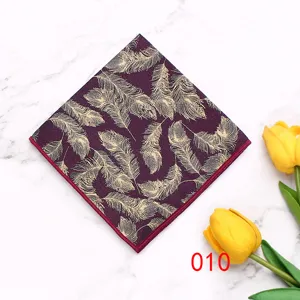Close-up view of men pocket square featuring golden feather print on dark red fabric.
