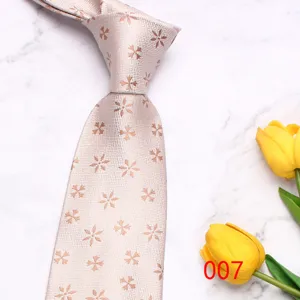 Detail view of light pink men's floral woven necktie on white marble with yellow tulips.