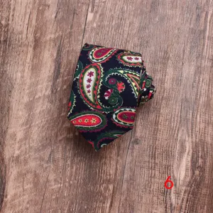 Detailopname van een herenstropdas van katoen met paisleymotief gerold op houten ondergrond.