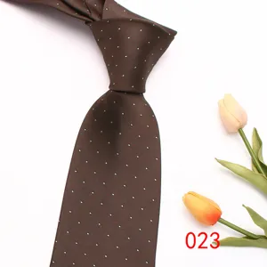 Brown necktie detail with white polka dots and elegant tulip prop on clean white background.