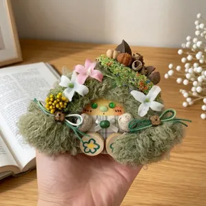Handmade moss doll detail shot, cute forest spirit plush hanging ornament with dried flowers.
