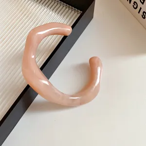 Detailed view of an acrylic irregular geometric open bracelet in light pink, minimalist.