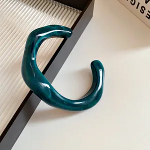 Detail shot of a dark green acrylic irregular geometric open bangle, minimalist jewelry design.