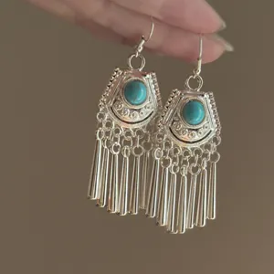 Detailed shot of vintage ethnic turquoise dangle earrings with metallic fringe design for women.