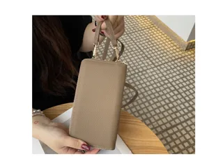 Detail view of genuine leather mini phone bag strap, showing fine texture and metal zipper.