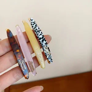Detalle de horquillas de pelo acrílicas en cuatro elegantes patrones con letras doradas.