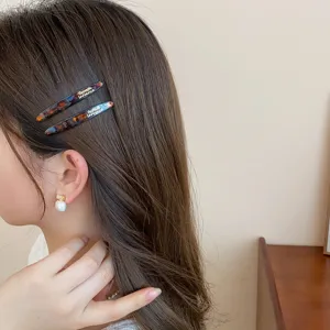 Detalle de pinza de pelo de acrílico con textura carey y elegante estampado de letras para mujer.