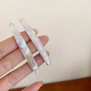 Detalle en primer plano de horquilla de acrílico jaspeado con letras doradas, elegante.