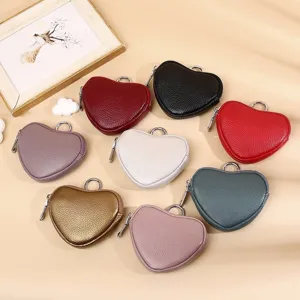 Detail view of colorful heart-shaped leather coin purses with metallic zipper and hanging ring.