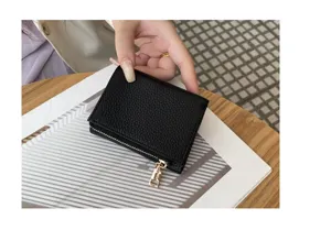 Compact black leather trifold mini wallet with gold zipper pocket for women's daily use.