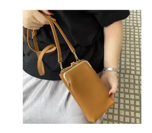 Detailed close-up of brown leather mini crossbody phone bag highlighting metal clasp and strap.