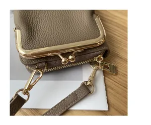 Close-up detail of genuine leather mini crossbody phone bag with kiss lock metal frame.