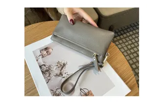 Grey leather wristlet wallet detail, compact purse with double zipper and hand strap.