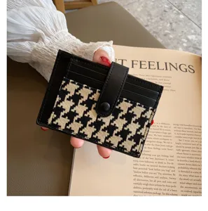 Detail shot of a chic black and white houndstooth mini card holder with snap closure.