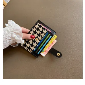 Compact houndstooth leather card holder with multiple slots and chic snap closure for women.