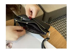 Detail view of black leather clutch wallet showing multiple zipper compartments and large capacity.