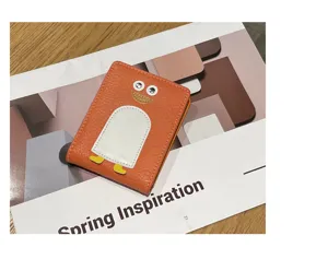Nahaufnahme des süßen orangen Lederkartenhalters mit witzigen Wackelaugen und Pinguin-Design.