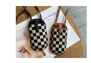 Gedetailleerd beeld van de stijlvolle mini crossbody telefoontas met ruitjes en lederen riem.