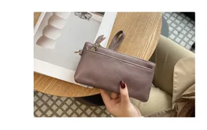 Detail view of the elegant leather wristlet clutch bag, featuring secure zippers and soft texture.