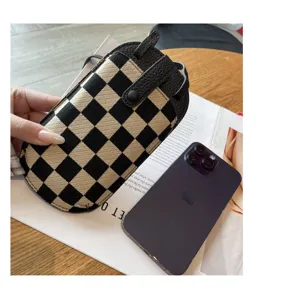 Kleine canvas en lederen crossbody telefoonstas met modieus zwart-wit ruitjespatroon.