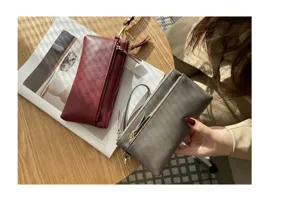 Close-up detail showing genuine leather long clutch bag with multiple zipper compartments.