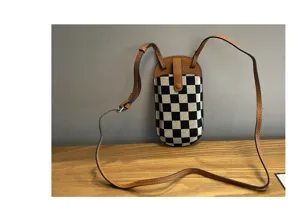 Mini ruitjes canvas telefoon tas detailweergave met lederen afwerking en riempje.