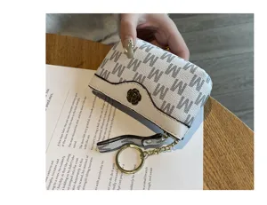 Detail view of white monogram coin purse with flower snap button and metal keychain ring.