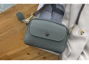 Exquisite genuine leather crossbody bag in sage green with brown strap and flap closure.
