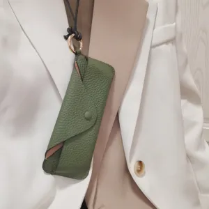 Detail shot of green genuine leather neck-hanging glasses case with metal ring strap storage.