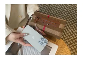 Γυναικεία τσάντα clutch από καμβά με κομψό ριγέ σχέδιο, δερμάτινες λεπτομέρειες και λουράκι καρπού.