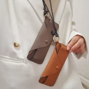 Leather glasses case detail showing genuine cowhide texture, lanyard, and snap button closure.
