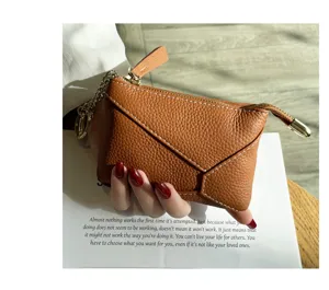 Detail view of a brown genuine soft leather coin purse with zipper closure and chain accent.