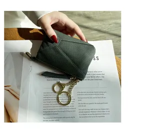 Detailed view of dark green leather coin purse zipper pocket and metal key ring design.