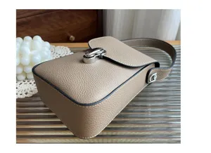 Detailed shot of taupe leather phone bag with metal turn-lock and texture surface.