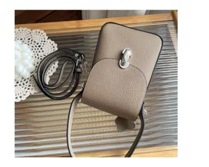 Genuine leather phone bag detail showing quality texture, metal lock and adjustable strap.