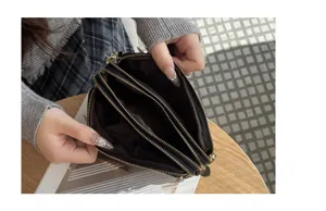 Detailansicht des Damen Leder-Clutch-Innenraums mit drei praktischen Reißverschlussfächern.