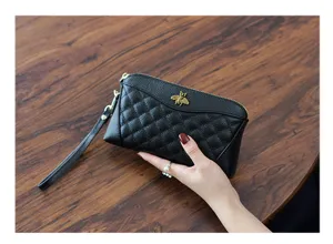 Genuine leather quilted clutch wallet with metal bee detail and wrist strap close-up view.