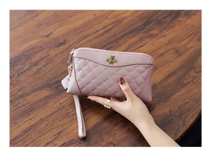 Detailed view of women's quilted leather clutch wallet featuring metal bee decor and wrist strap.