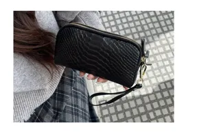 Nahaufnahme des schwarzen Kroko-Muster Leder-Clutch-Portemonnaies mit Doppelreißverschluss.